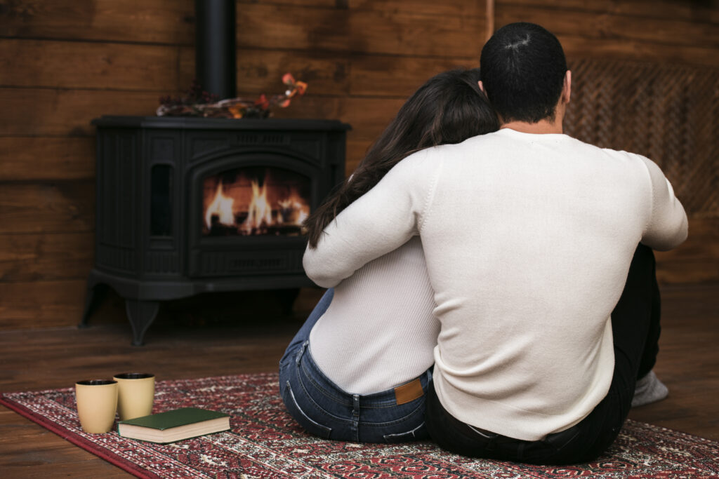 Husband and wife cuddled under a blanket by a firepit, representing warmth and intimacy rekindled through intentional love