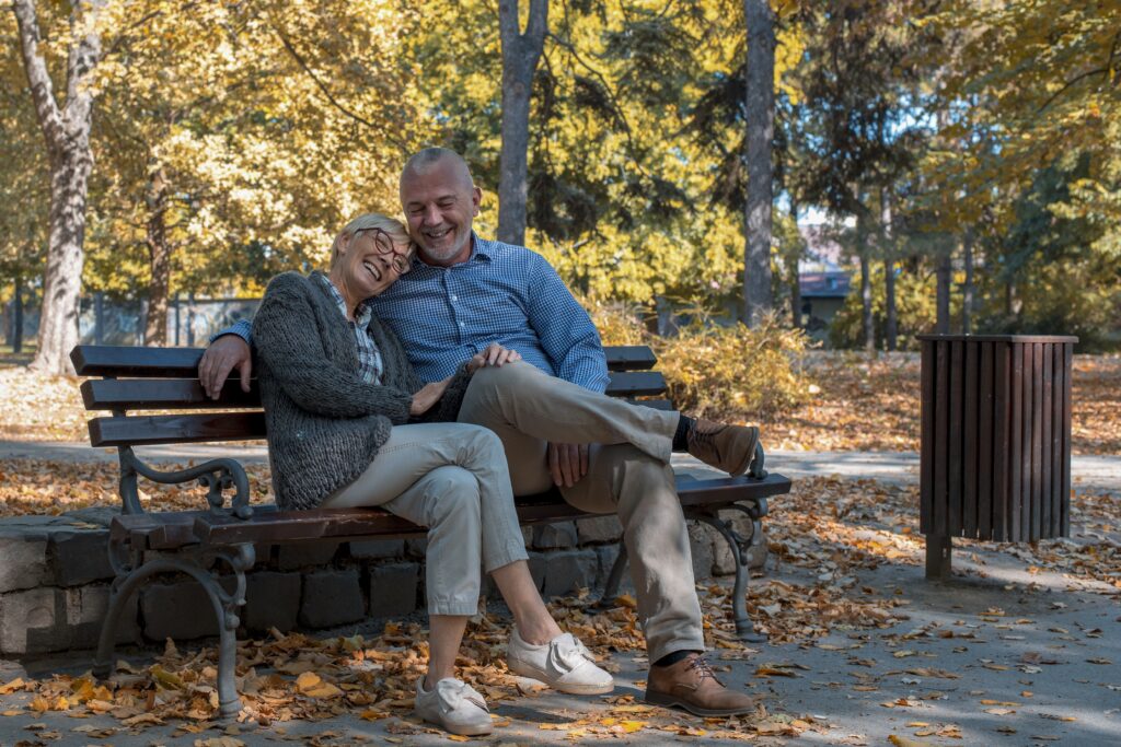 Elderly married couple sitting close on a bench, showing a lifetime of daily commitment