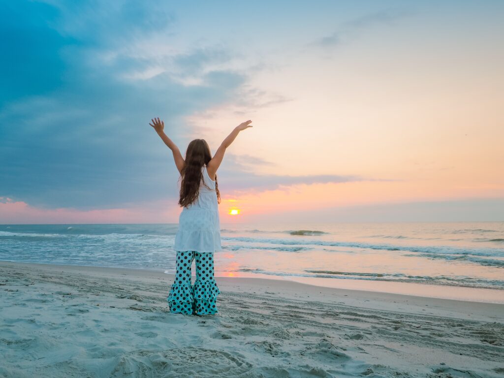 Individual standing with arms open at sunrise, symbolizing emotional freedom and spiritual renewal