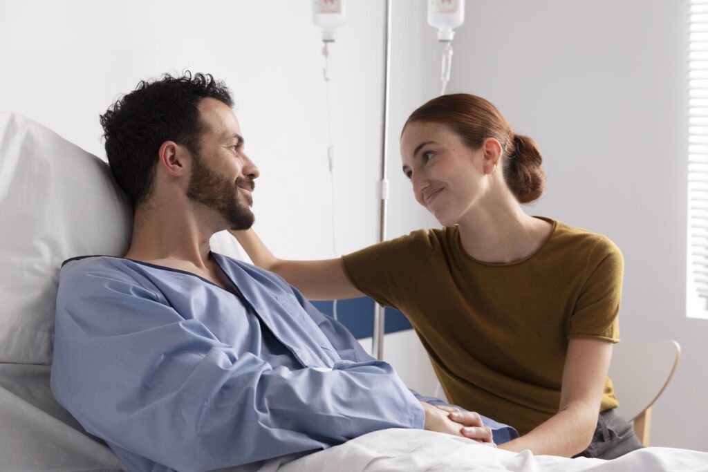 Husband holding his wife's hand in a hospital room, representing love that stays in sickness and difficulty