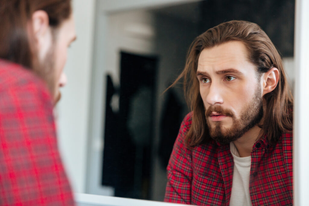 Person looking into mirror with concern, symbolizing identity confusion and emotional dependency