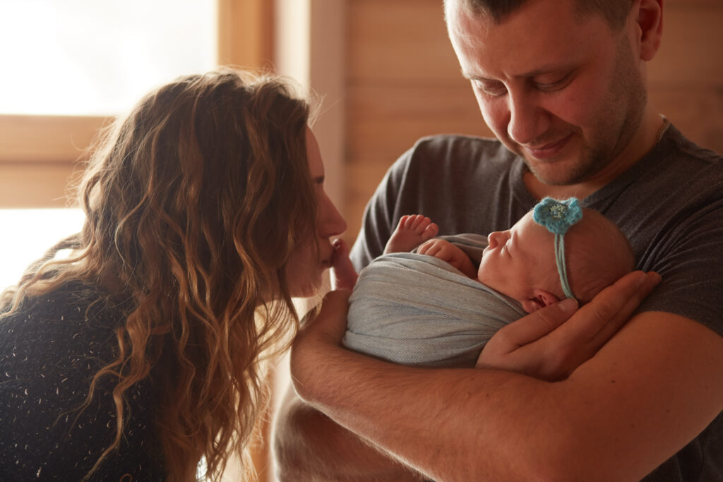 New parents smiling together while holding their baby, showing flexibility during life transitions.