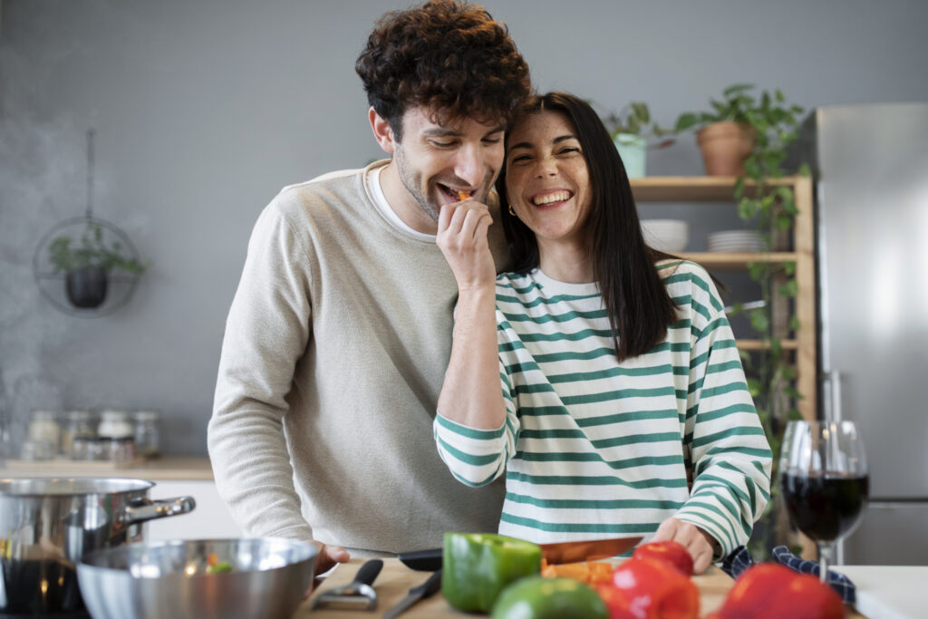 "Married couple preparing dinner together and laughing, representing the joy in daily acts of love and partnership