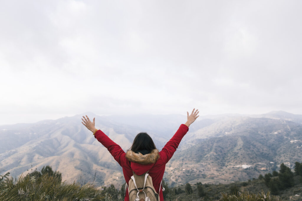 Person standing at sunrise with raised hands in worship, representing freedom and identity in God