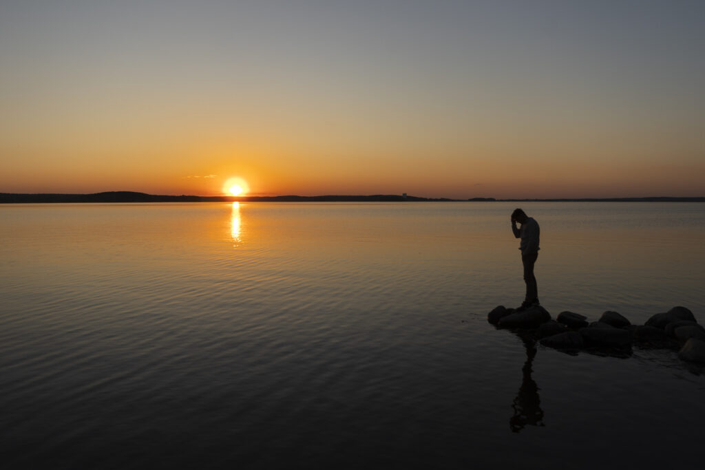 ggestion: A peaceful sunrise over a quiet lake with a person standing still at the edge ALT Text: "Person standing in stillness at sunrise by a calm lake, representing trust in God’s timing and letting Him fight your battles