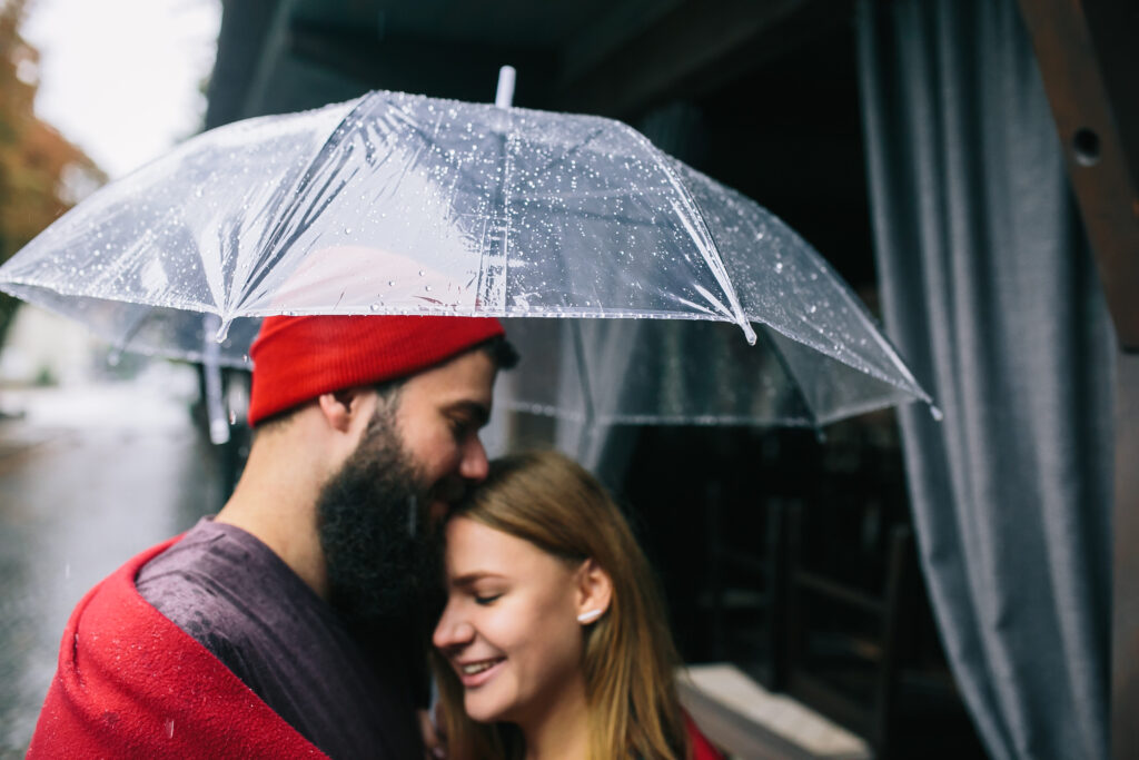 Married couple standing together under an umbrella in the rain, symbolizing endurance through life’s storms