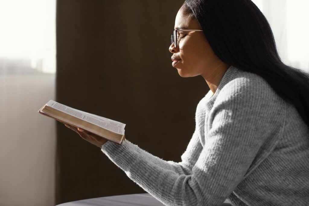 Woman holding Bible and 'Beloved' journal, anchoring her identity in Christ and personal devotion