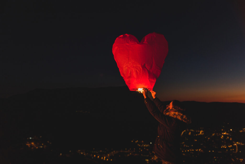 Releasing a paper lantern during sunset symbolizing letting go