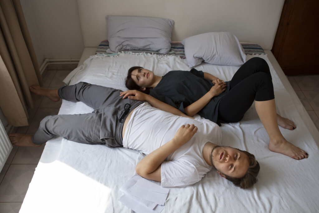 Emotionally disconnected couple lying back-to-back in bed, reflecting loneliness in a marriage