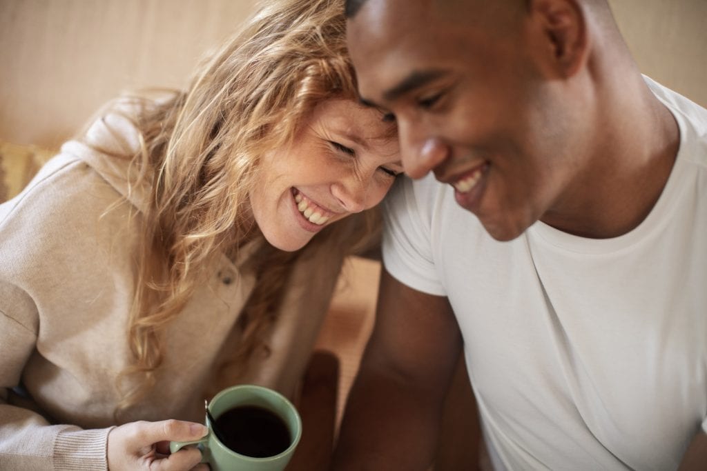 Couple sharing morning coffee and laughter, showing daily emotional investment