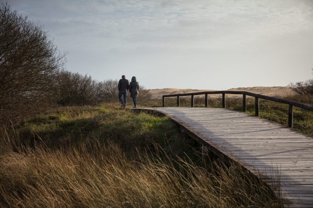 Married couple walking side by side on a wooded path, symbolizing a journey of growing together