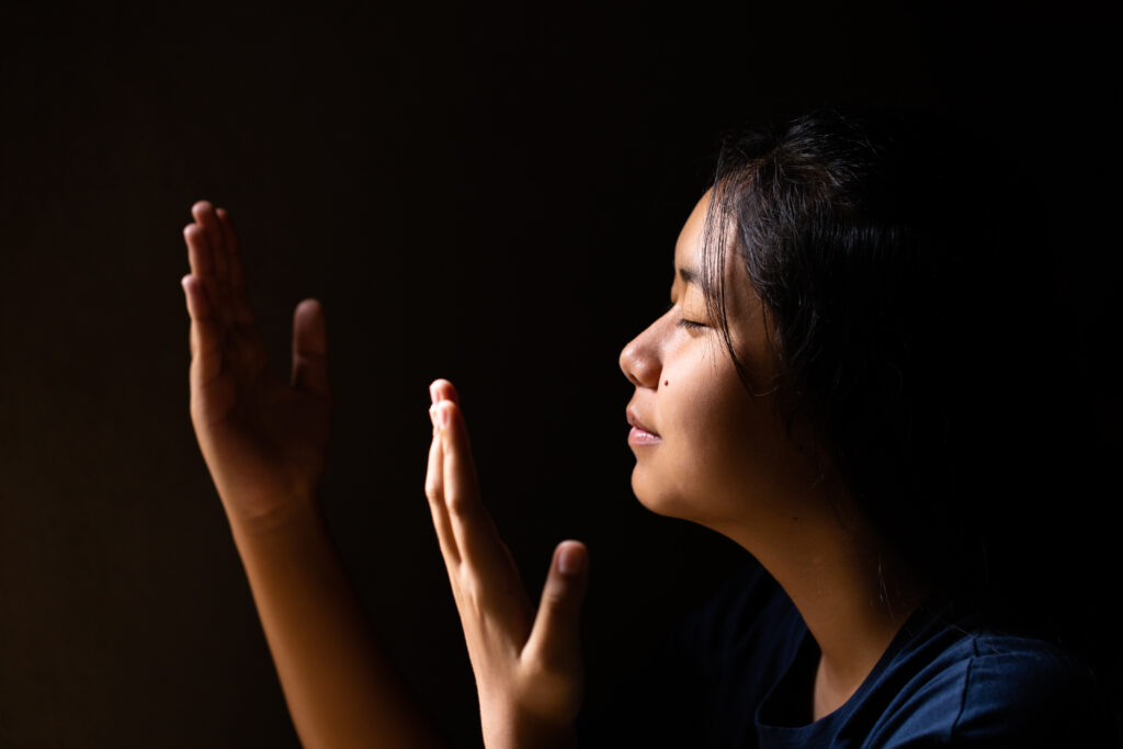 Woman with eyes closed and hands lifted in worship