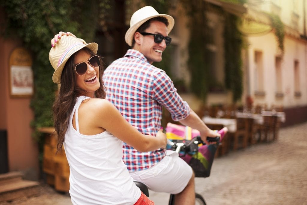 Married couple laughing during bike ride, symbolizing fun and play in relationships