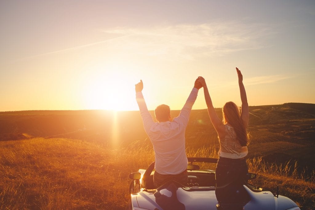 Married couple standing on mountaintop at sunrise, representing the journey from amateur to elite love 
