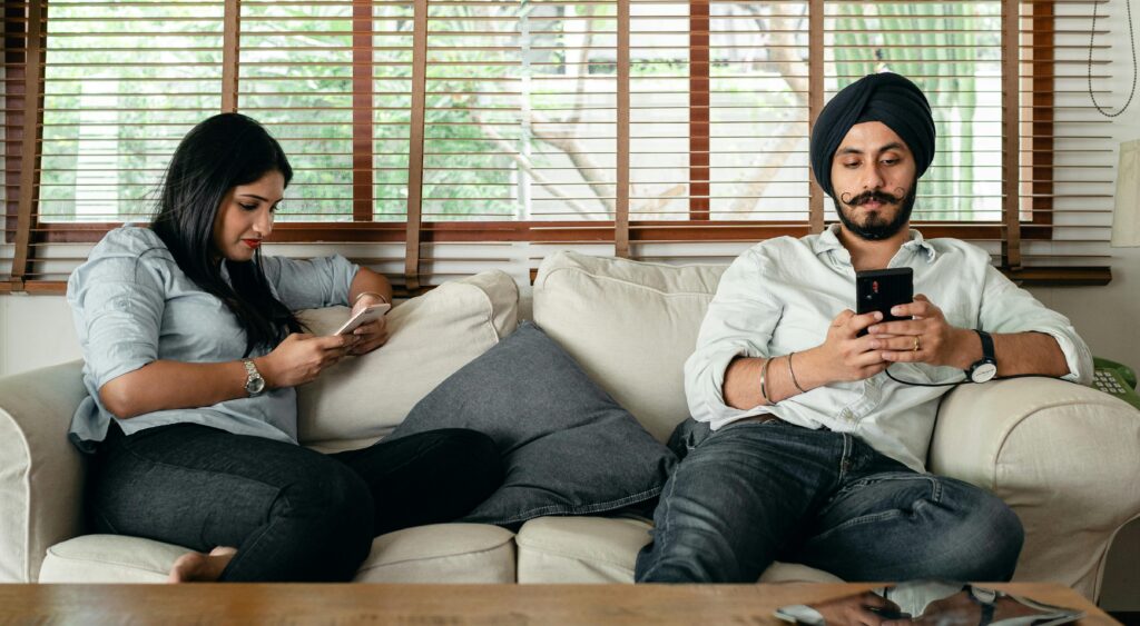 A couple sitting on opposite ends of a couch, looking away.