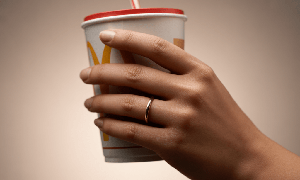 Hand holding oversized soda as metaphor for emotional baggage in marriage.