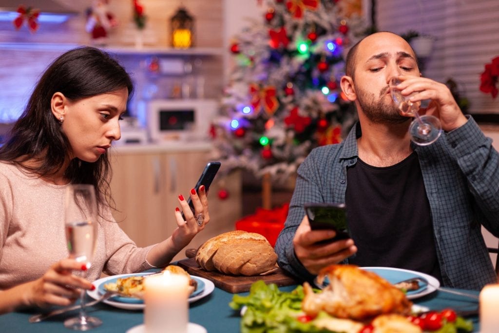 Distracted couple at dinner, symbolizing lack of emotional presence.