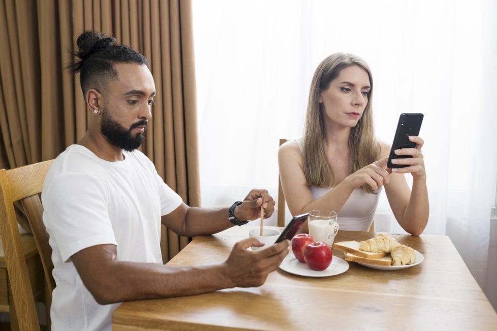 Married couple distracted by phones during dinner