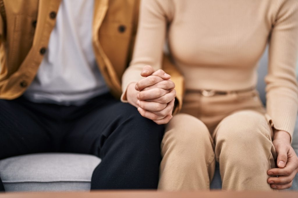 Couple holding hands during conflict resolution, showing love through small acts even during tension