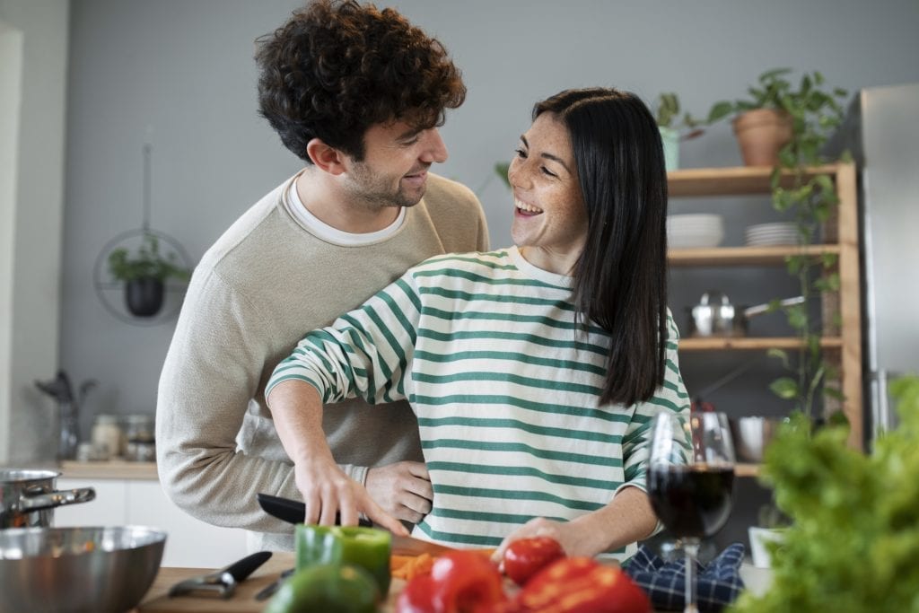 Husband and wife laughing in the kitchen, choosing to focus on joyful moments.
