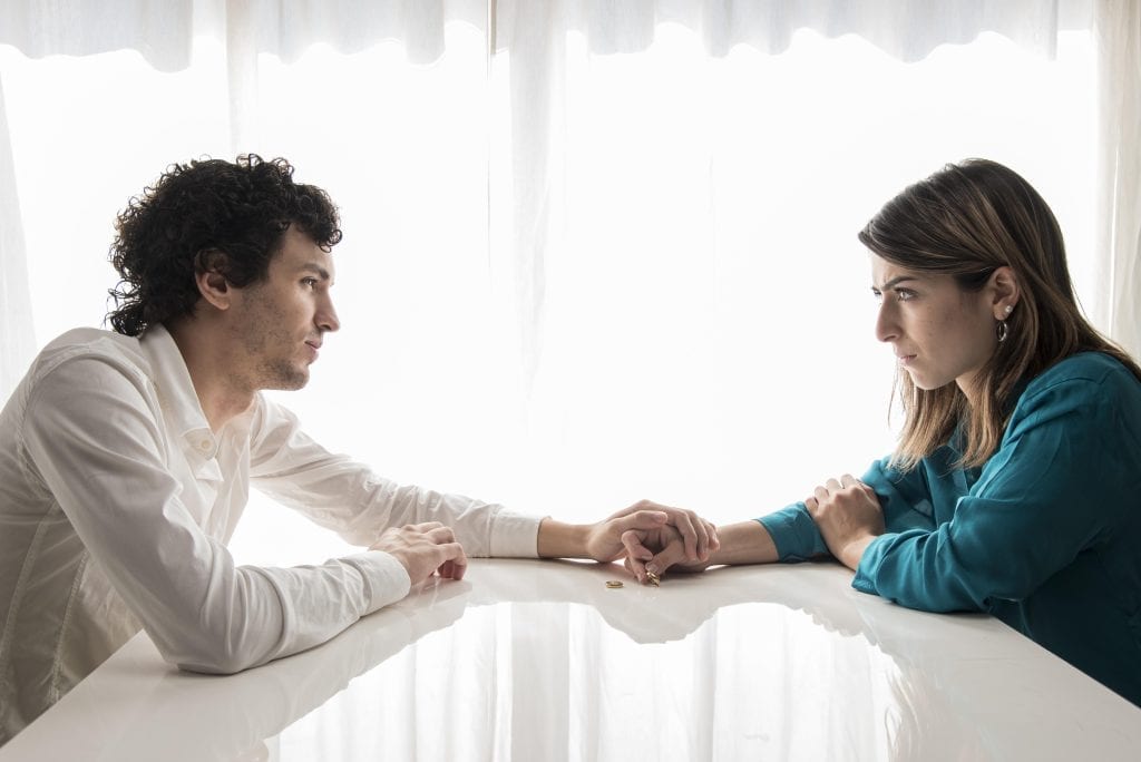 Partner reaching for their spouse in a gesture of reconciliation after emotional hurt.