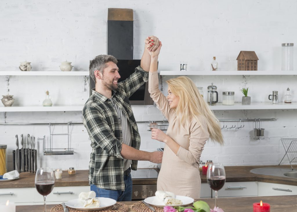 Happy couple dancing in the kitchen, embracing joyful connection through growth