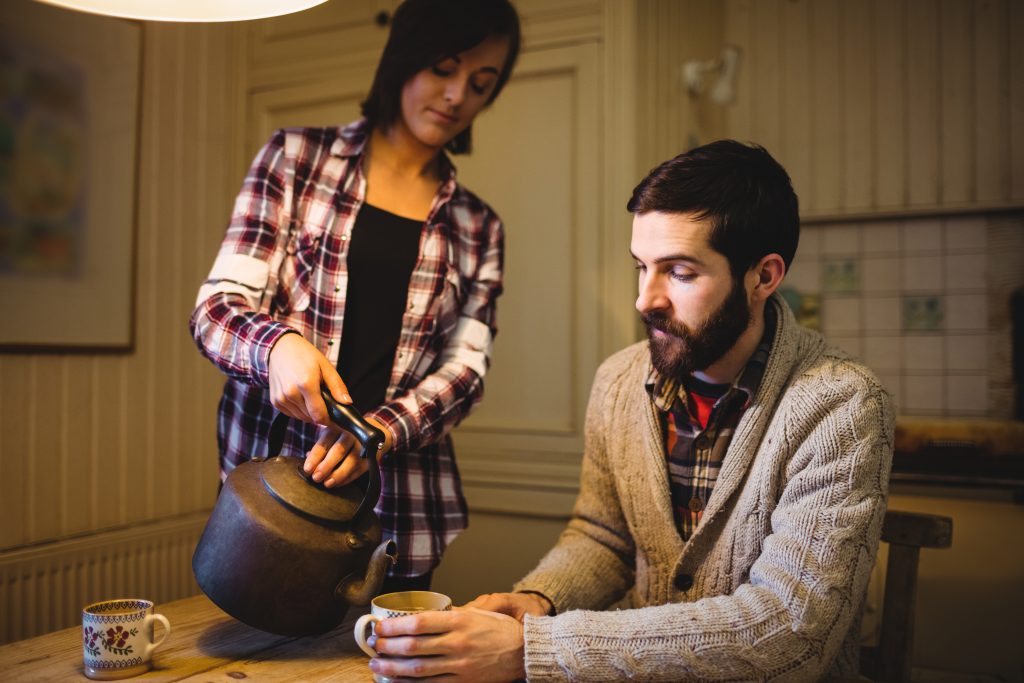 Spouse offering comfort with tea, showing love through calm presence in conflict