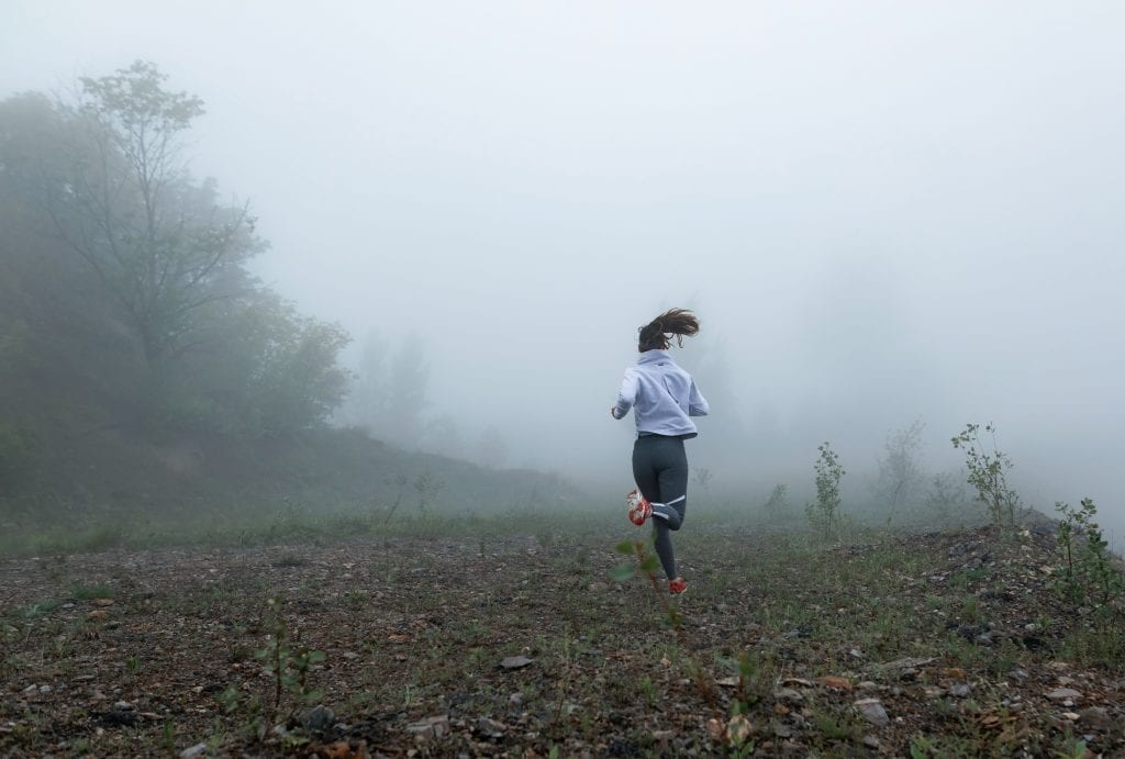 Runner training in the rain, symbolizing emotional growth happening in the storm.