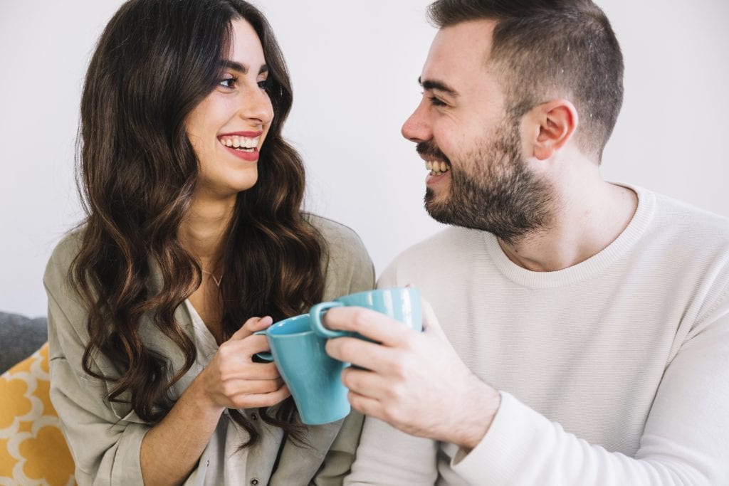 Married couple sharing coffee and smiling at each other, symbolizing positive agreement.