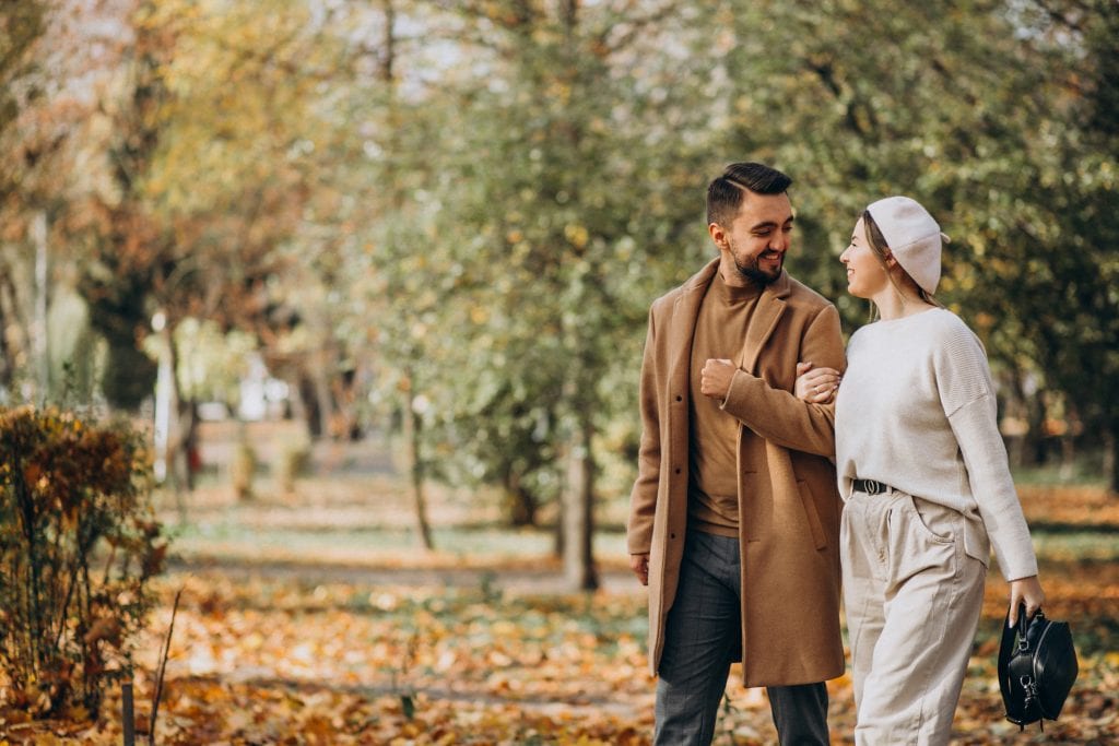 Married couple walking through falling leaves, symbolizing emotional maturity through the seasons of a long marriage