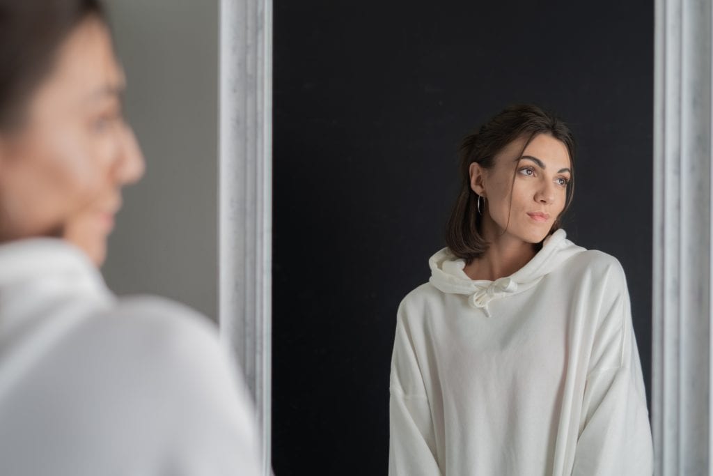 Person confidently looking into a mirror, symbolizing self-assurance and rejection of false labels.