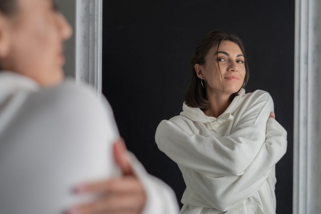 Woman reflecting in the mirror, symbolizing self-image shaped by agreement.