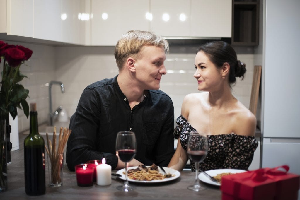 Couple smiling at dinner table celebrating small marriage wins.
