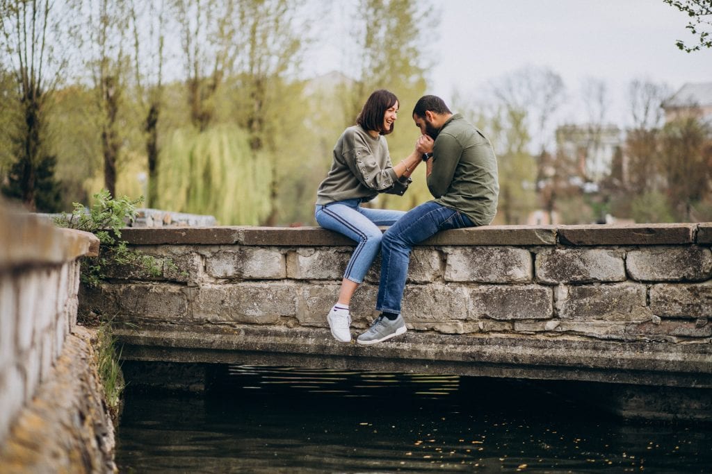 couple sitting on bridge-protecting connection while waiting for alignment