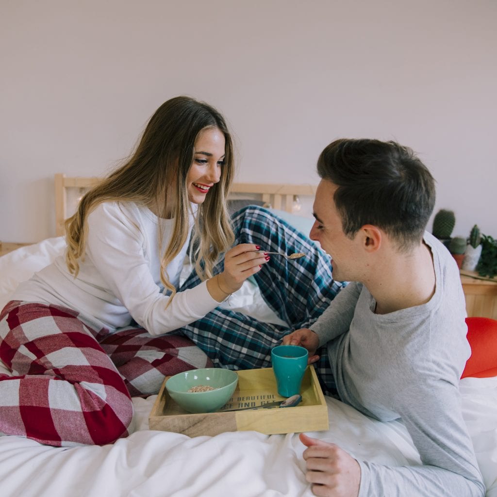 Partner serving breakfast in bed representing small acts of service.