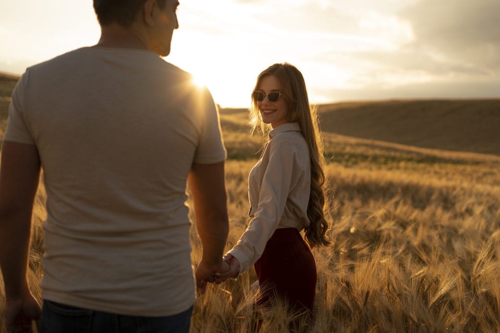 Couple holding hands at sunrise symbolizing gratitude and awareness during peaceful times.