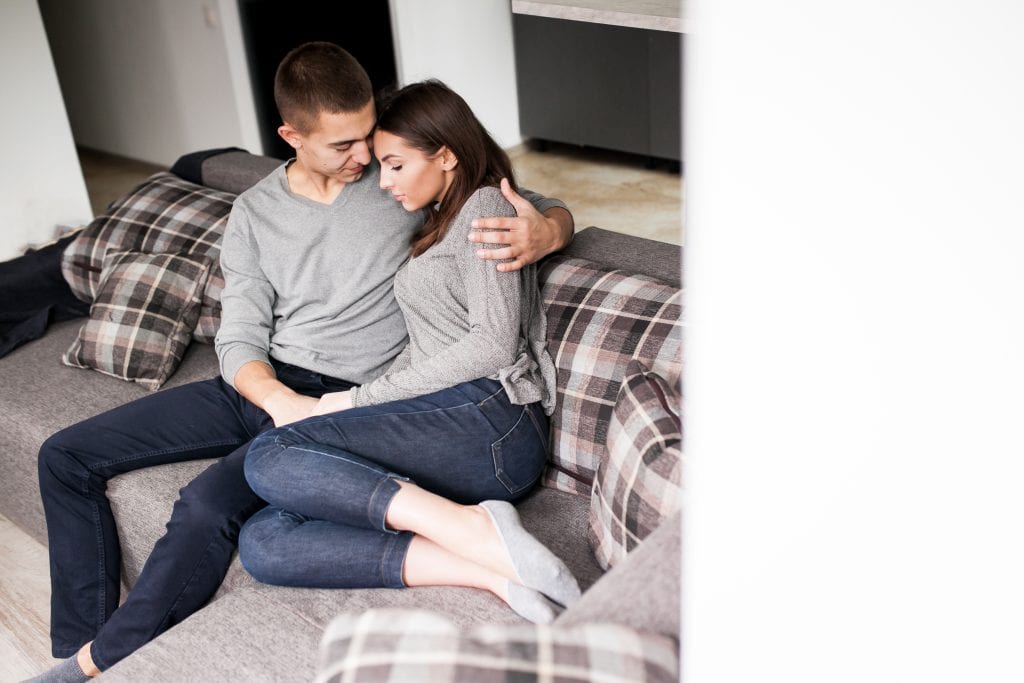 Couple sitting close during difficult talk symbolizing empathy under stress.