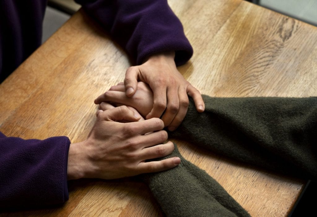 Married couple holding hands over a table, choosing connection in the present moment