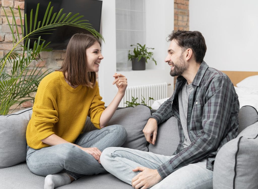 Husband and wife sitting on a couch, one speaking and the other listening attentively instead of talking over
