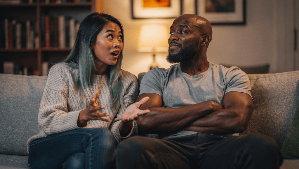 Husband rolling his eyes while wife talks on the couch, illustrating quiet contempt before moving from eye-rolls to empathy